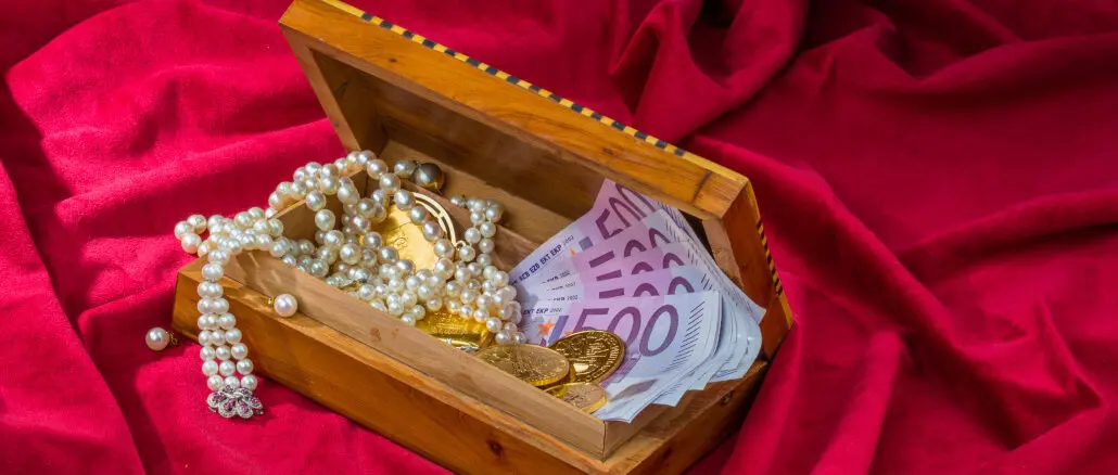Gold, Schmuck und Bargeld in einer kleinen Truhe